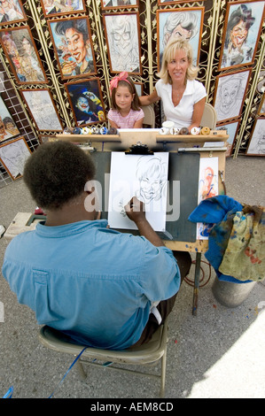 Artiste de la rue de sexe masculin dessine une caricature d'une mère et fille Banque D'Images