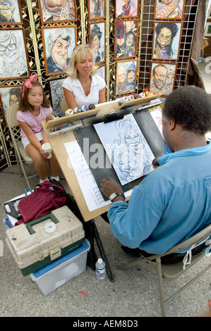 Artiste de la rue de sexe masculin dessine une caricature d'une mère et fille Banque D'Images