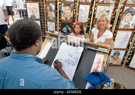 Artiste de la rue de sexe masculin dessine une caricature d'une mère et fille Banque D'Images