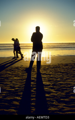 Silhouette en frontlighting d'un homme qui regarde un couple de jogging sur la plage dans la ville de Agadir maroc sud Banque D'Images
