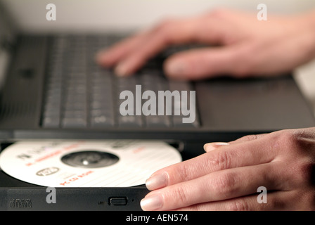 Femme d'insérer un disque dans le lecteur de CD-Rom d'un ordinateur portable Banque D'Images