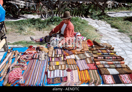 Femme tissant et assise à côté de cadeaux tissés traditionnels, marché Pisac Pisac,, près de Cusco, Pérou Banque D'Images