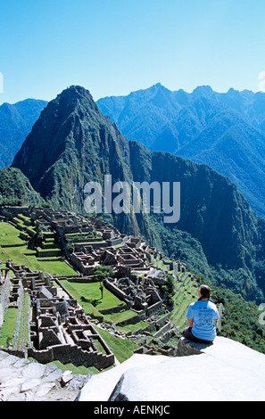 Les ruines Inca de Machu Picchu, terrasses, visiteur assis sur rebord, et Huayna Picchu, Pérou Banque D'Images