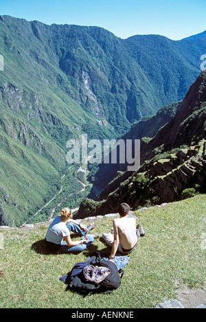 Les ruines Inca de Machu Picchu, les terrasses, les visiteurs assis sur la terrasse, Pérou Banque D'Images