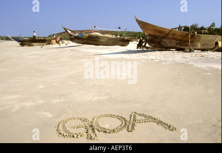 Inde Goa Goa écrit dans le sable avec des bateaux de pêche Banque D'Images