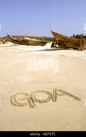 Inde Goa écrit dans le sable sur la plage vide avec bateaux de pêche Banque D'Images