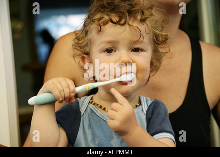 Kleinkind 18 Monate alt JONI mit Bernsteinkette putzt nach dem Essen mit Gesicht verschmiertem Milchzaehne Parution Modèle seine Banque D'Images