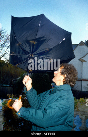 Homme avec parapluie souffler à l'intérieur dehors sur Jour de vent Banque D'Images