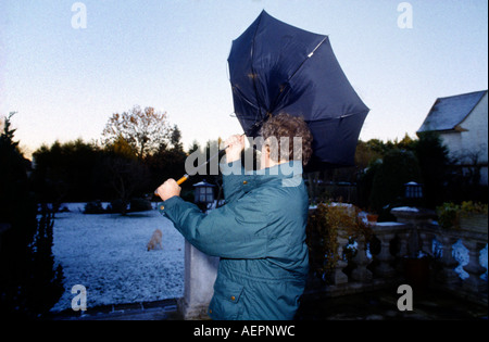 Homme avec parapluie souffler à l'intérieur dehors sur Jour de vent Banque D'Images