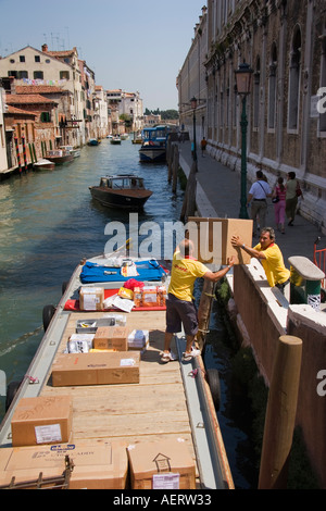 Les hommes sur boîtes charge DHL voile alonside l'Ospedale dei Libreri près de Venise Italie Banque D'Images