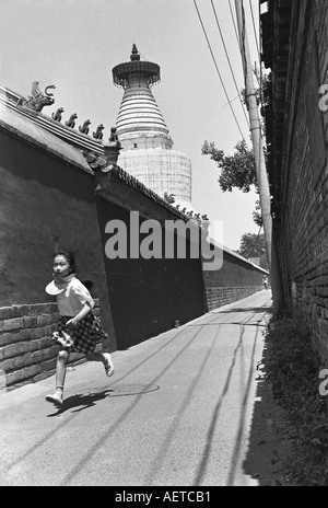 Une écolière s'exécutant dans un hutong petit à côté du Temple des Nuages Blancs à Pékin Chine 2003 Banque D'Images