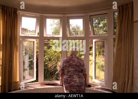 Femme âgée de 81 ans à la recherche de sa chambre à l'avant fenêtre, Londres, Royaume-Uni. Parution du modèle de droit (MR). Banque D'Images