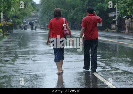 Couple, homme et femme portant tous deux un t-shirt rouge, marchant sous la pluie de mousson, Bombay, Mumbai, Maharashtra, Inde, Asie Banque D'Images