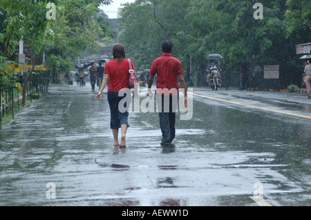 Couple, homme et femme portant tous deux un t-shirt rouge, marchant sous la pluie de mousson, Bombay, Mumbai, Maharashtra, Inde, Asie Banque D'Images