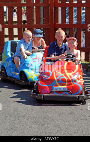 Les enfants s'amuser au volant des karts autour d'une piste à un parc d'amusement Banque D'Images