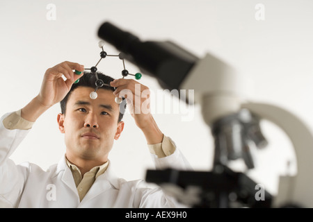 Scientist avec microscope holding molecular model Banque D'Images