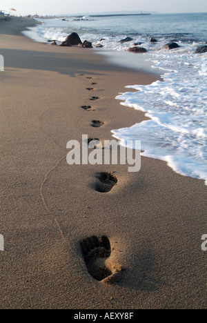 Empreintes de pas sur le sable à la plage avec des vagues et l'océan Banque D'Images
