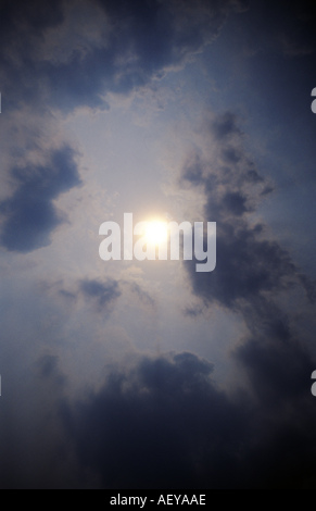 Soleil voilé derrière des nuages gris Banque D'Images