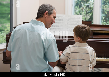 Le père et le jeune fils à jouer du piano Banque D'Images