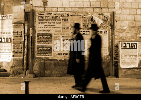 Les juifs hassidiques marchant devant des panneaux de propagande Jérusalem israël Banque D'Images