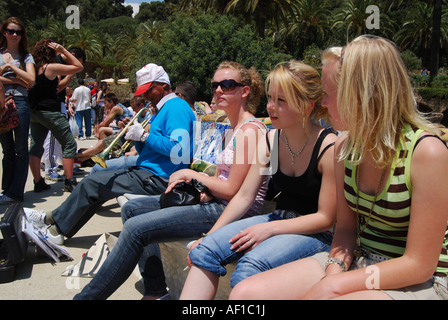 Groupe scolaire des adolescents avec busker assis sur bancs de parc en Parc Guell Barcelone Banque D'Images