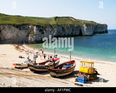 Une petite plage et falaises de craie, avec des bateaux de pêche et un tracteur jaune au North Landing Flamborough, North Yorkshire UK. Banque D'Images