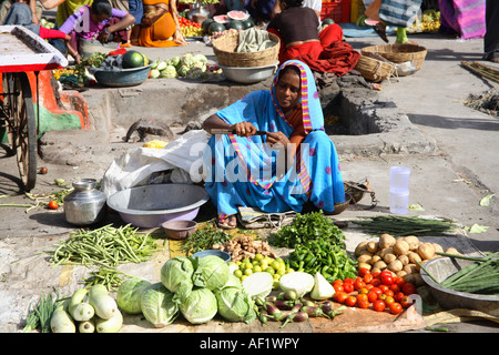 Négociant de marché nettoyant les ongles avec des légumes disposés sur terre dans le marché, Vanakbara Fishing Village, DIU Island, Gujarat, Inde Banque D'Images