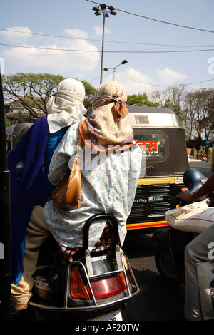 Vue arrière des femmes indiennes portant des foulards de tête en scooter dans la circulation intense, Pune, Inde Banque D'Images