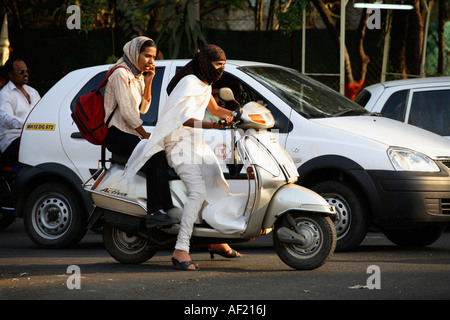 Jeune femme indienne conduisant un scooter sans casque portant salwaar kameez dans la circulation intense, Pune, Inde Banque D'Images