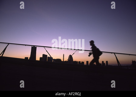 Un photographe, en silhouette, se promène devant les gratte-ciel de Yokohama, vu de la jetée d'Osanbashi au coucher du soleil. Kanagawa, Japon Banque D'Images