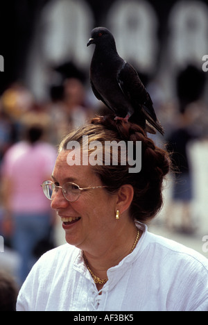 Pigeon assis sur la tête d'une femme à lunettes, la Place Saint Marc, Venise, Italie Banque D'Images