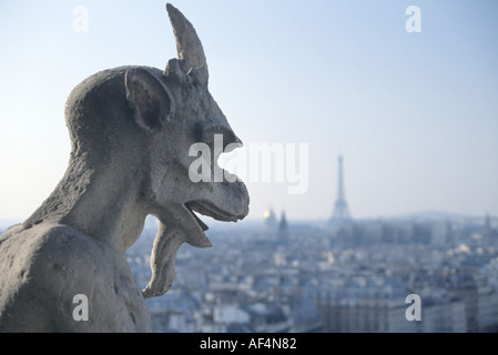 Une gargouille garde le haut de la cathédrale Notre Dame au-dessus de Paris France avec la Tour Eiffel l'accent doucement sur l'horizon Banque D'Images