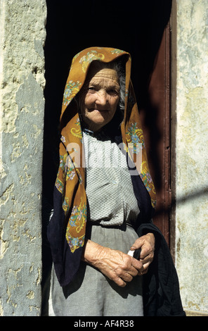 Jolie vieille dame dans la vieille porte de pierre de Sunny side street au milieu des années 60, dans le vieux quartier de Lisbonne, Estremadura Portugal Banque D'Images