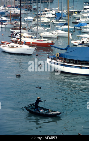 Taxi d'eau traditionnels déménagement par stern paddle sur fond de yachts de luxe à Causeway Bay Hong Kong Chine refuge typhon Banque D'Images