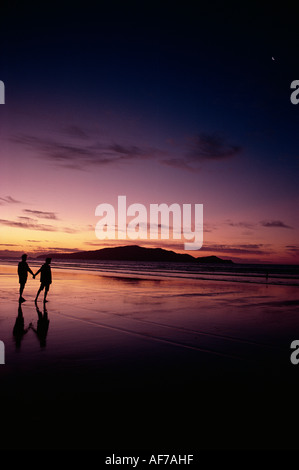 Nouvelle-Zélande. Île de Kapiti. Jeune couple sur la plage au coucher du soleil. Banque D'Images