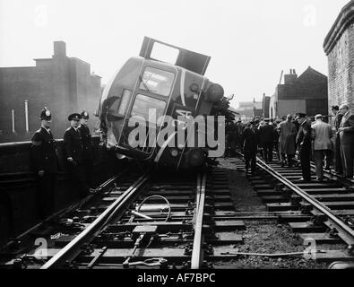 Vintage photographie en noir et blanc d'une foule de personnes y compris l'affichage de la police de locomotive a déraillé sur le côté incliné. Banque D'Images