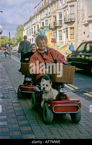 Les femmes âgées à l'aide de scooters électroniques pour la mobilité en ville avec un chien à bord Banque D'Images