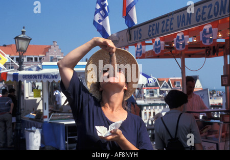 Pays-bas Volendam young woman eating hareng cru dans la manière typiquement néerlandais Banque D'Images
