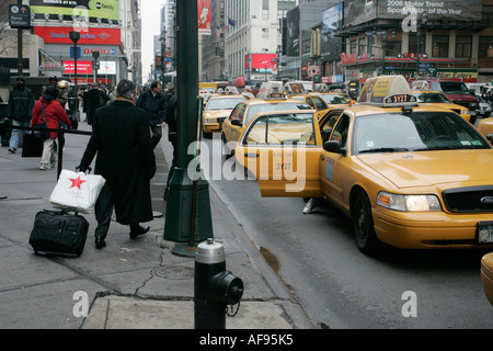 Homme d'âge moyen l'homme bien habillé avec des approches valise cabine jaune sur station de taxis devant le Madison square garden Banque D'Images