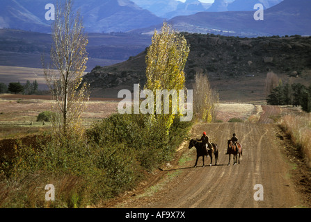 Deux hommes noirs de l'équitation le long d'une route de poussière à distance dans une zone semi-aride de l'Afrique du Sud, de l'environnement montagneux Banque D'Images