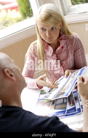 Une jeune femme avec des agents immobiliers à la recherche de renseignements pour les maisons et appartements Banque D'Images