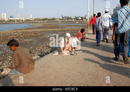 Mendiant sur Causeway en direction de la mosquée Haji Ali Dargah dans Mumbai, Inde Banque D'Images