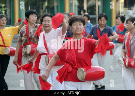 Les femmes avec batterie faire la gymnastique à l'extérieur tôt le matin de la ville de Yinchuan Ningxia Chine Août 2007 Banque D'Images