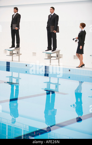 Businessmen standing sur startng blocs, woman holding megaphone Banque D'Images