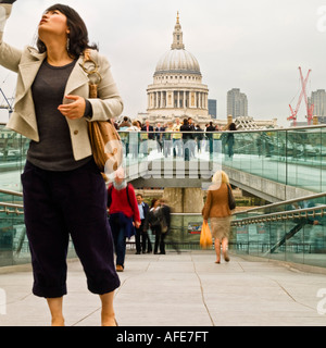 Woman taking photo en face du pont du millénaire, loin de St Paul à Londres bankside ciel laiteux pâle hiver vêtements sombres Banque D'Images