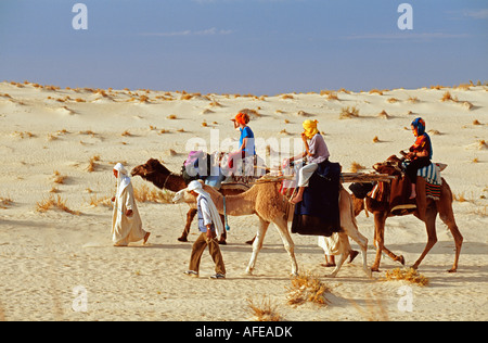Tunisie Tozeur, désert du Sahara, les touristes à cheval sur le désert du Sahara à dos de chameau Banque D'Images