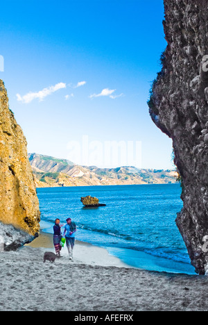 Deux personnes marchant avec le chien sur la plage de Nerja, Espagne Banque D'Images