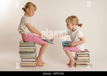 Deux filles assis sur une pile de livres lire ensemble Banque D'Images