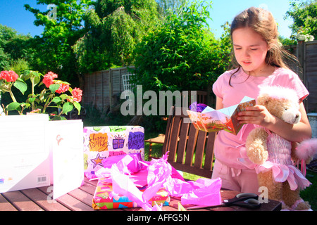 Joyeux anniversaire célébration de la petite fille, qui s'ouvre avec enthousiasme ses cadeaux d'anniversaire Banque D'Images