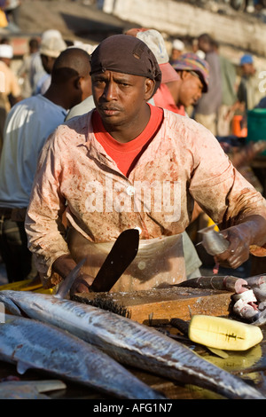 L'homme en costume traditionnel préparer un poisson à vendre dans la ville de pierre de Zanzibar, marché aux poissons Banque D'Images